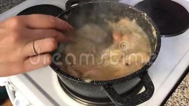 虾用平底锅煮。 一个女人用勺子把它们混合在一起。